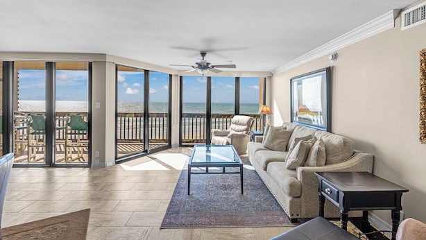 Ein geräumiges Wohnzimmer mit einem großen Glasfenster zum Balkon, Deckenventilator, Sofa und Couchtisch.