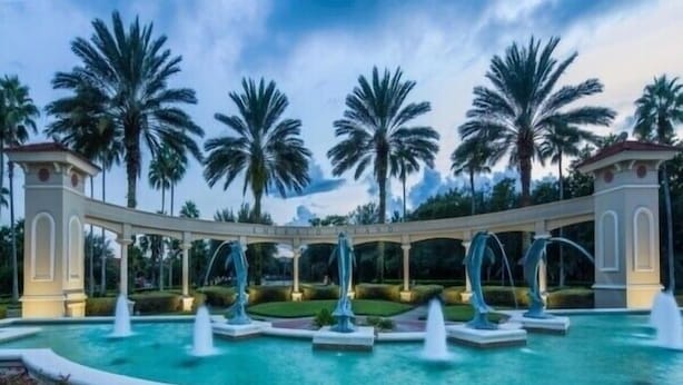 A pool area with multiple fountains and palm trees in the background. - 8BR lakefront Disney home w themed rms HarryPotter Frozen ToyStory Mario Royal (Kissimmee)
