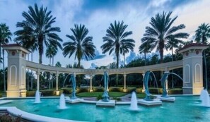 A pool area with multiple fountains and palm trees in the background. - 8BR lakefront Disney home w themed rms HarryPotter Frozen ToyStory Mario Royal (Kissimmee)