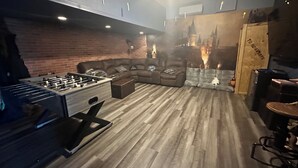 A cozy living room with a foosball table, a brick wall, and a fireplace. - 8BR lakefront Disney home w themed rms HarryPotter Frozen ToyStory Mario Royal (Kissimmee)