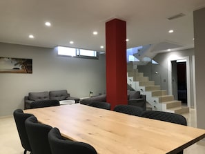 A modern living room with a wooden dining table, grey sofas, and a red accent wall. - Villa Orihuela Costa (Orihuela)