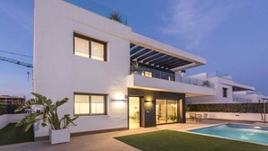Une maison moderne à deux étages, dotée d’une piscine, de grandes fenêtres et d’une pelouse bien entretenue.