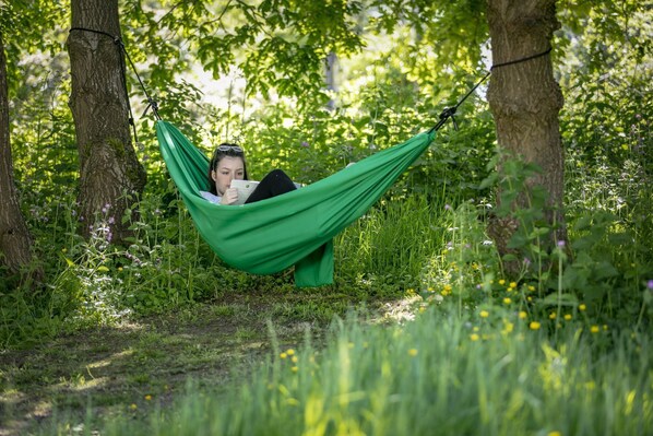 A person relaxing in a hammock in a wooded area. - Lloyds Meadow Glamping Delamere Chester (Chester)