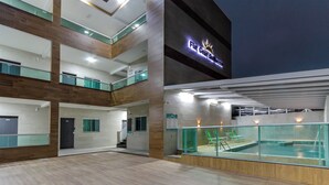 Un hotel de varios niveles con piscina en la planta baja y múltiples balcones, y un cartel que dice 'Flat Gear Boutique'.