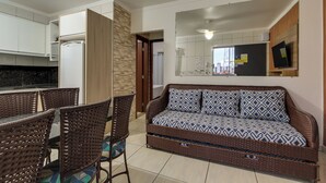 Un espacio moderno para relajarse con sofá, mesa de comedor, sillas y una cocina al fondo.