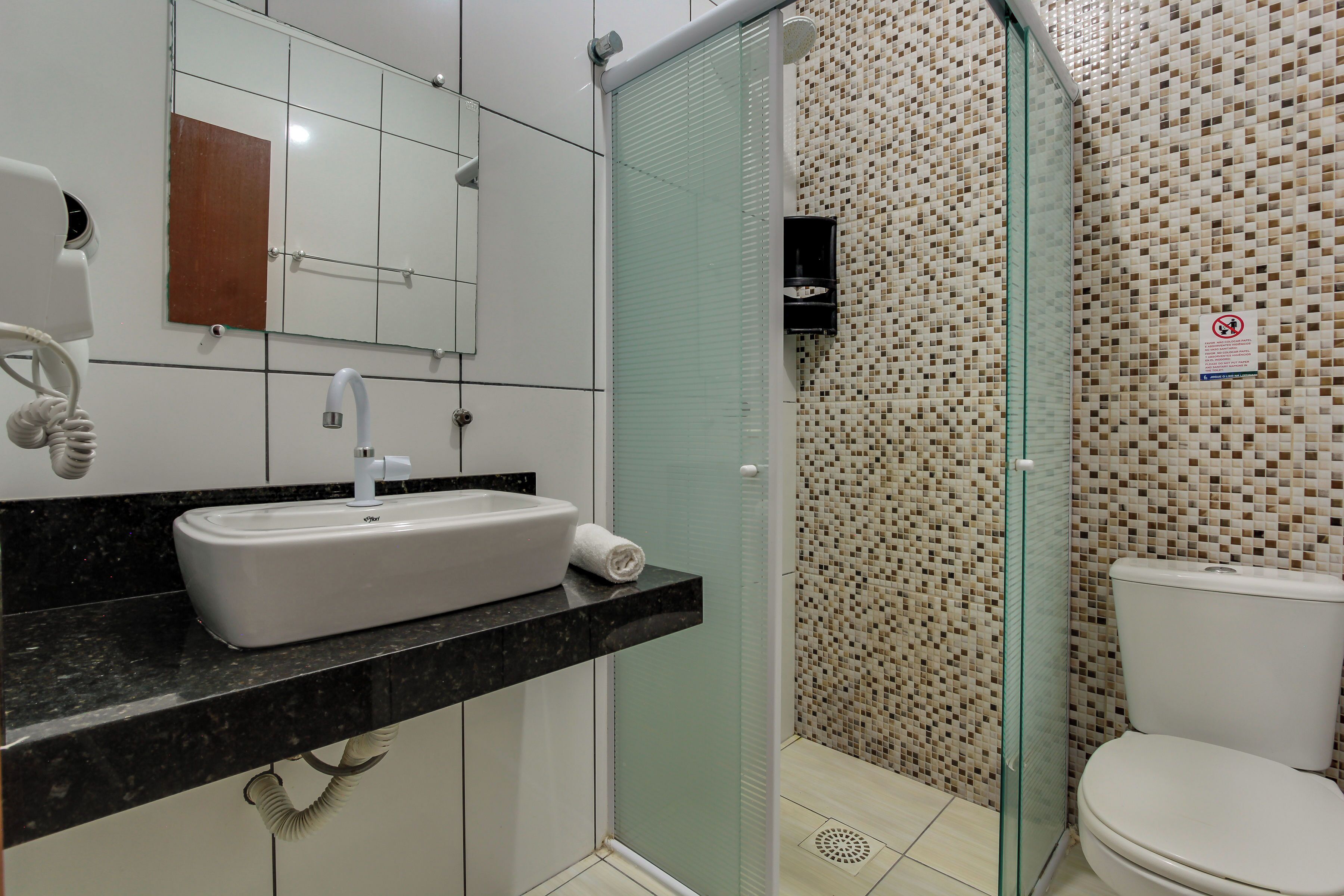 A bathroom with a white sink, a glass shower enclosure, and a tiled wall.