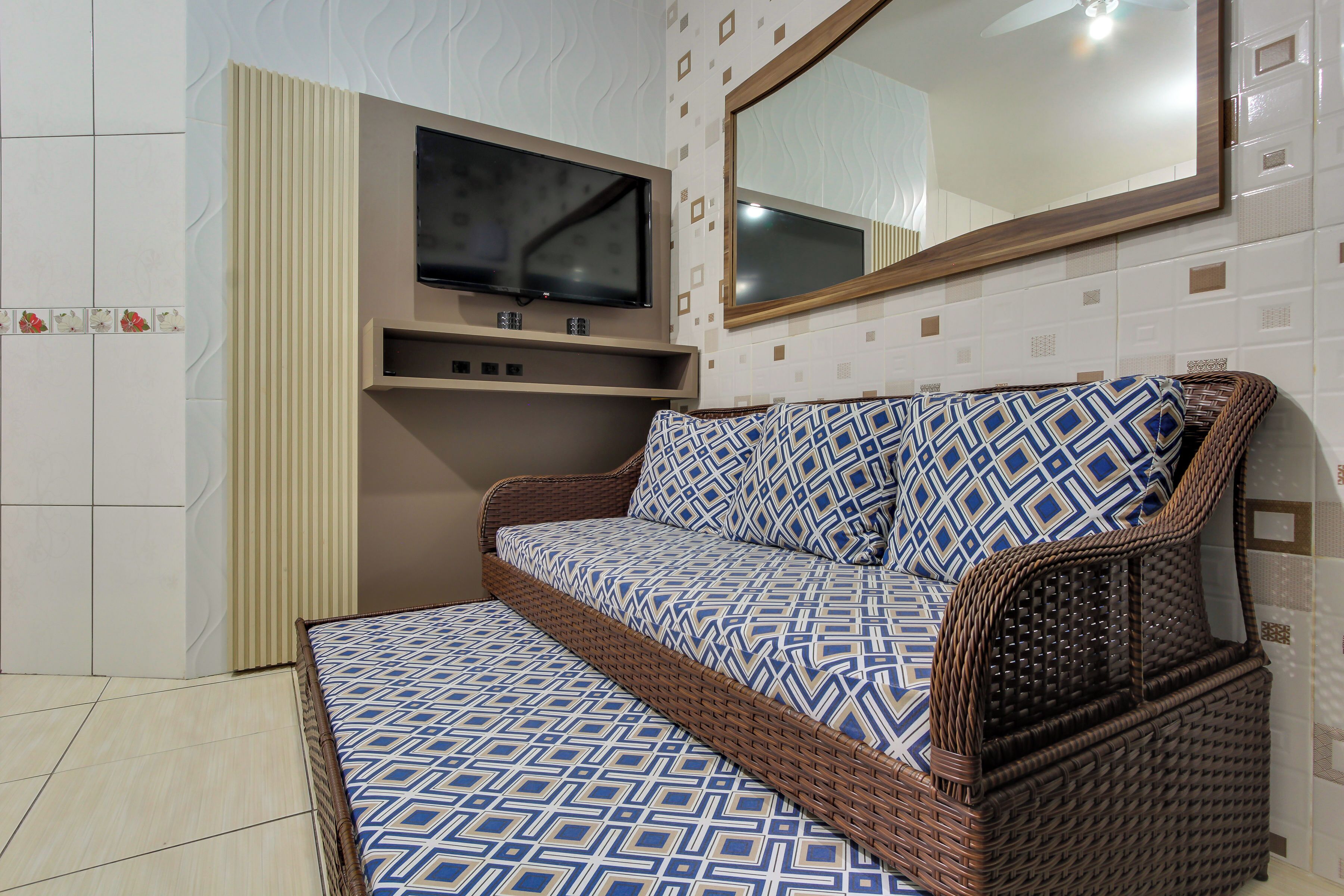 Una habitación con sofá cama, televisor de pantalla plana y un espejo en la pared.
