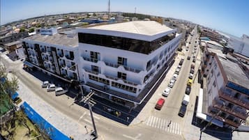 A modern building with a flat roof, multiple floors, and a large parking lot.