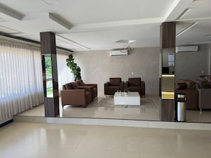 A modern lobby with a seating area, air conditioning units, and a plant.