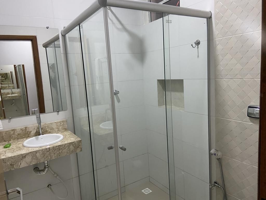 A modern bathroom with a glass-enclosed shower, a marble countertop sink, and a mirror.