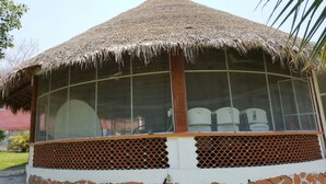 Il s’agit d’une structure à toit de chaume, dotée de fenêtres à croisillons, qui pourrait faire partie d’un bâtiment ou constituer un élément architectural indépendant.