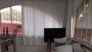 Un salon moderne avec un canapé, un téléviseur et un coin repas avec des chaises.