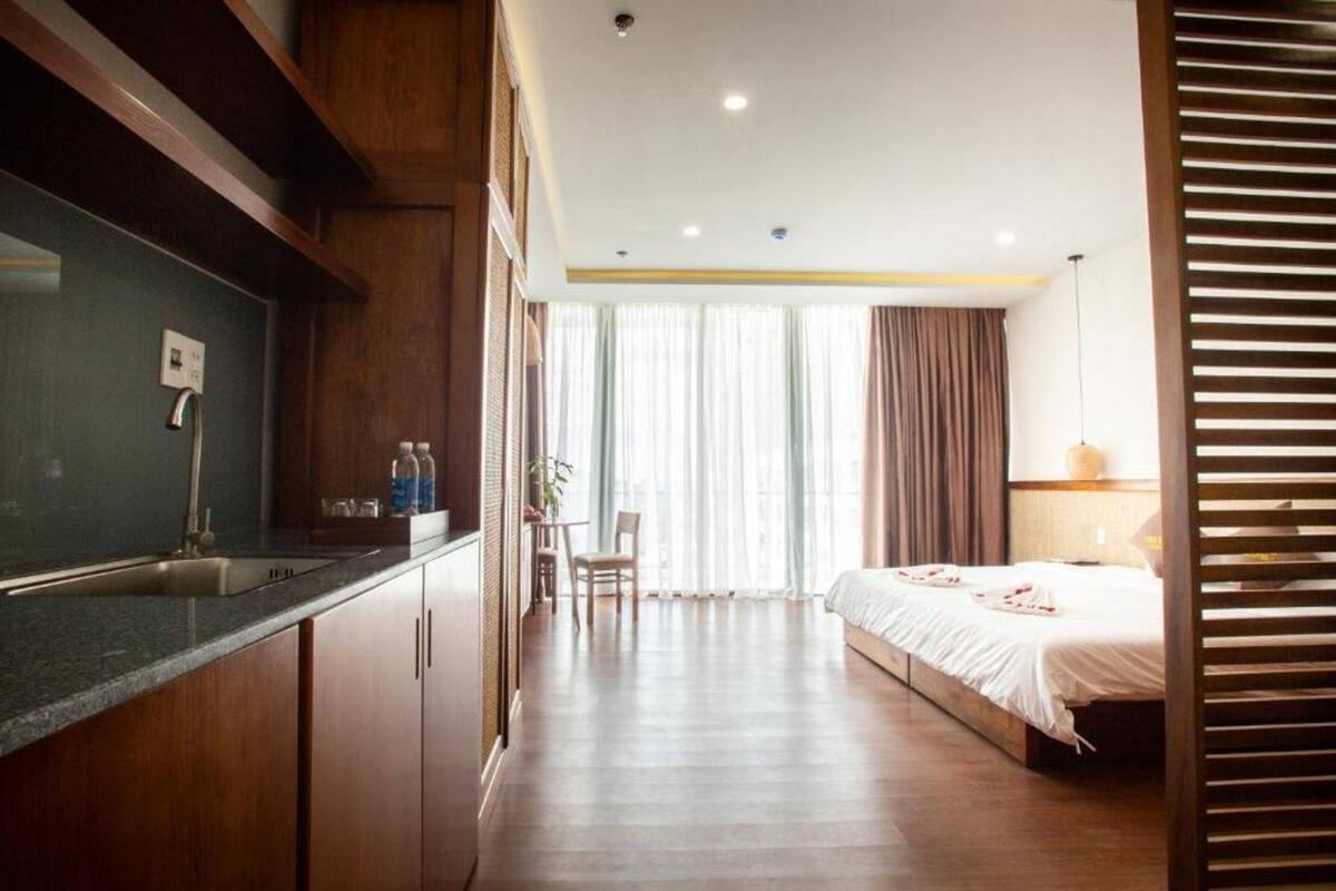 A hotel room with a kitchenette, a bed, a desk, and a view of the outdoors.