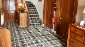 A staircase with a plaid carpet, wooden doors, and a fire extinguisher. - Gowanfield B&B (Dingwall)