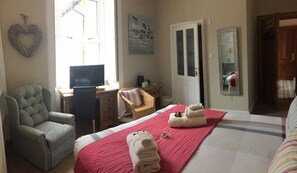 A hotel room with a bed, a desk with a computer, a chair, a TV, a door, and a mirror. - Gowanfield B&B (Dingwall)