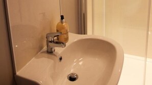 A bathroom with a round mirror, a sink, and a glass shower enclosure. - Gowanfield B&B (Dingwall)