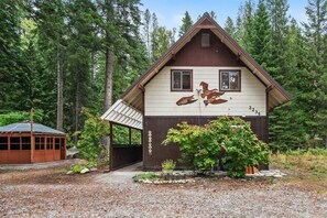 A cabin with a sloped roof, a covered porch, and a small garden area with rocks and plants.