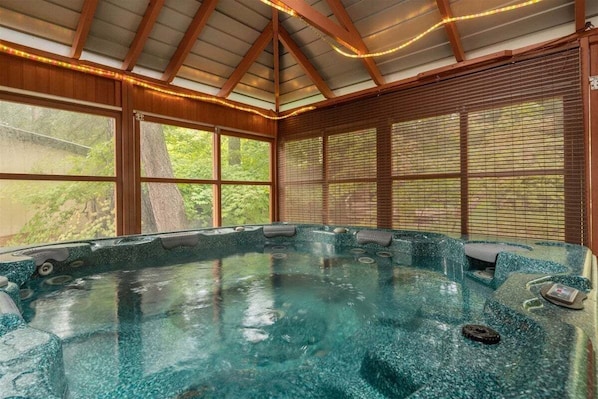 Ein Whirlpool mit freiem Blick auf die Umgebung, darunter ein großes Fenster und Holzbalken.