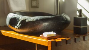 Un baño con un lavabo de piedra, un perchero para toallas y un espejo.
