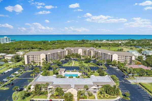 A hotel with multiple buildings, a central pool, and a parking lot.