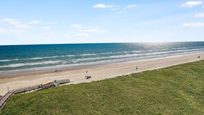 Une plage avec une promenade en bois qui mène au rivage, une plage de sable et l’océan.