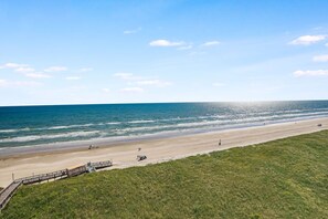 En strand med en träpromenad som leder ner till stranden, en sandstrand och havet.