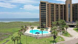 Un hôtel de grande hauteur doté d’une piscine, offrant une vue sur la plage et disposant d’un parking.