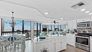 Une cuisine spacieuse dotée d’un grand îlot central, de meubles blancs et d’appareils électroménagers en acier inoxydable.
