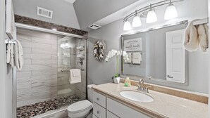 Une salle de bain moderne avec une douche en verre, un lavabo blanc et un grand miroir.