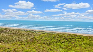 Eine Küstenlandschaft mit Strand, Meer und grüner Hügellandschaft.
