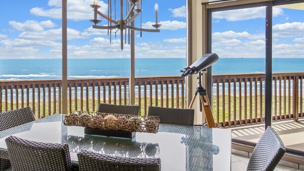 Ein Balkon mit Tisch, Stühlen, einem Teleskop und einer Chandelier.