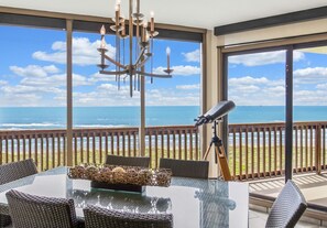 Ein Balkon mit Tisch, Stühlen, einem Teleskop und einer Chandelier.