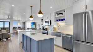 A modern kitchen with a central island, stainless steel appliances, and pendant lighting.