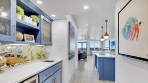 A modern kitchen with blue cabinets, a white countertop, and a view to the dining area.