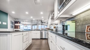 A modern kitchen with white cabinetry, a black countertop, and a view of the city.