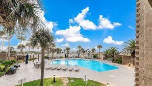 A swimming pool with lounge chairs and palm trees.
