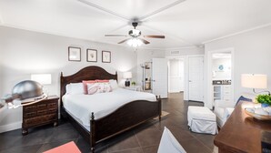 A bedroom with a wooden bed, a nightstand, a desk, and a ceiling fan.