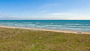 Une plage offrant une vue dégagée sur l’océan, avec un véhicule garé sur le sable.