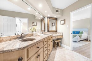 A bathroom with a double sink vanity, wooden cabinets, and a large mirror. - Sandpiper Condominiums 306, Panoramic Gulf Views w/ direct access to Mustang Island/Port A beaches. (Port Aransas)