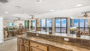 Una cocina amplia con una isla grande, armarios de madera y vistas al océano a través de ventanas amplias.