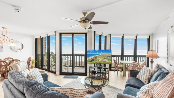 Un salon spacieux avec un grand canapé, une table basse et un balcon offrant une vue sur la plage.