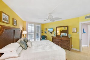 Une chambre à coucher comprenant un lit, une commode, un ventilateur de plafond et un téléviseur.