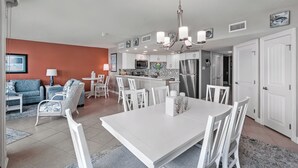 Une cuisine moderne avec des meubles blancs, un îlot central et un réfrigérateur en acier inoxydable.