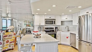 Una cocina moderna con armarios blancos, electrodomésticos de acero inoxidable y una isla central.