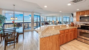 A spacious kitchen with a large island, wooden cabinets, and a view of the ocean. - Sandpiper Condominiums 303, Panoramic Gulf Views w/ direct access to Mustang Island/Port A beaches. (Port Aransas)