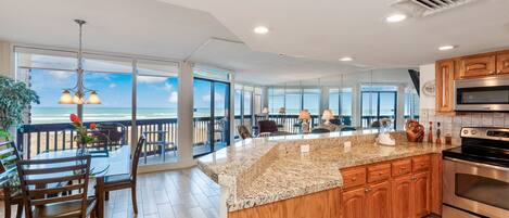A spacious kitchen with a large island, wooden cabinets, and a view of the ocean.