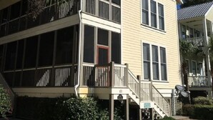 Un edificio a due piani con un balcone e una zona coperta, immerso nel verde.