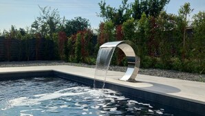 Ein moderner Pool im Freien mit einem einzigartigen, runden Wasserspiel.