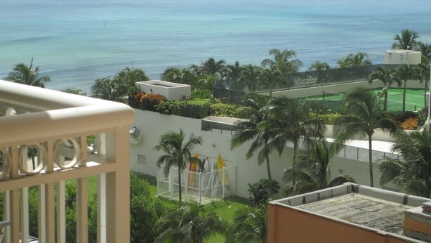 Vista de una zona costera con cancha de tenis, palmeras y un edificio con un letrero que dice 'Ocean Two'.