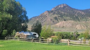 A white RV parked in a grassy field with a mountain in the background.